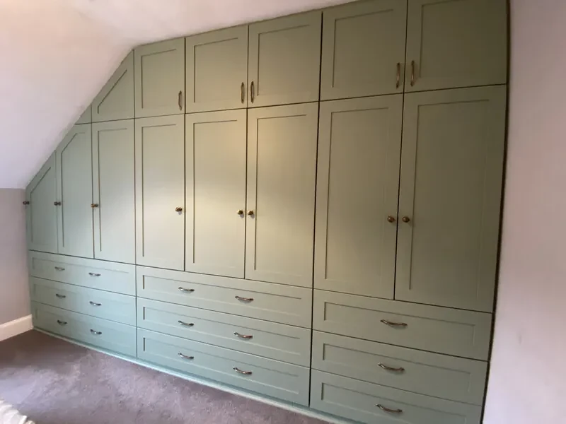 Fitted wardrobes and drawers below a sloping ceiling.